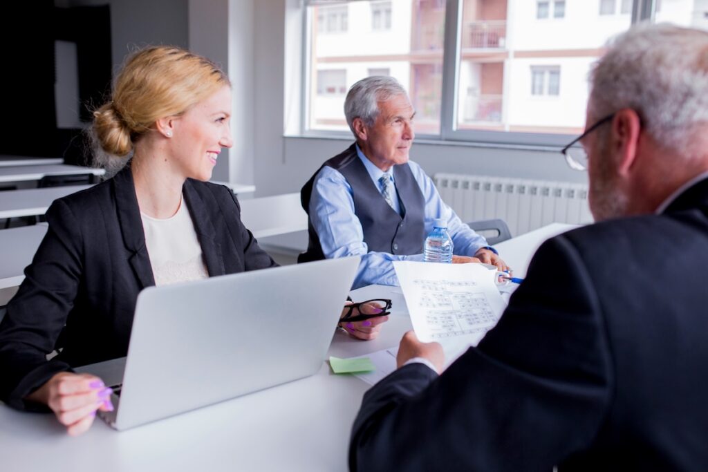 Three professionals working together in an office, a young woman and two older men