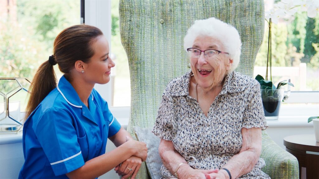 Uniformed member of staff talking to a resident in a retirement home